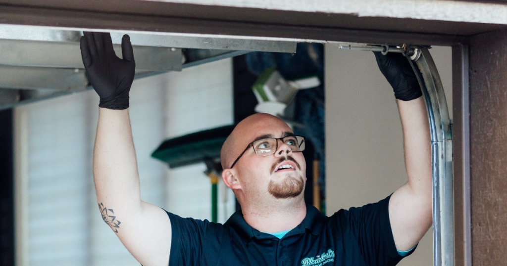 Man checks garage door track alignment above.