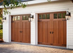 Two elegant, wooden carriage-house style garage doors with black hardware handles and decorative hinges under lantern sconces, illustrating a high-quality maintenance standard or the outcome of a professional garage door repair.