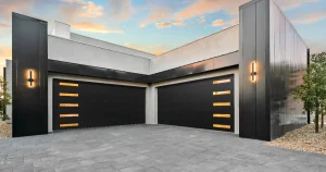 An ultra-modern, upscale home exterior featuring a spacious concrete driveway and two sleek, matte black sectional garage doors with narrow, vertically stacked translucent horizontal windows that glow warmly from within, demonstrating a premium garage door replacement.
