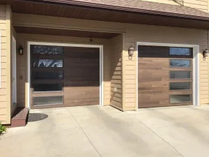Two modern, dark-wood plank sectional garage doors featuring vertically stacked rectangular glass windows along one side, beautifully highlighting a contemporary garage door style.
