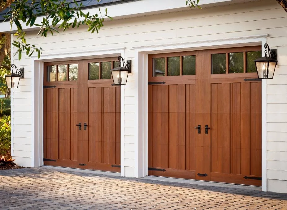 Two elegant, wooden carriage-house style garage doors featuring decorative black hinges and hardware, showing off a classic wood garage door style.