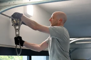 A professional technician using a specialized tool to secure and adjust a garage door's overhead spring assembly, highlighting a key safety check for garage door break-in prevention.